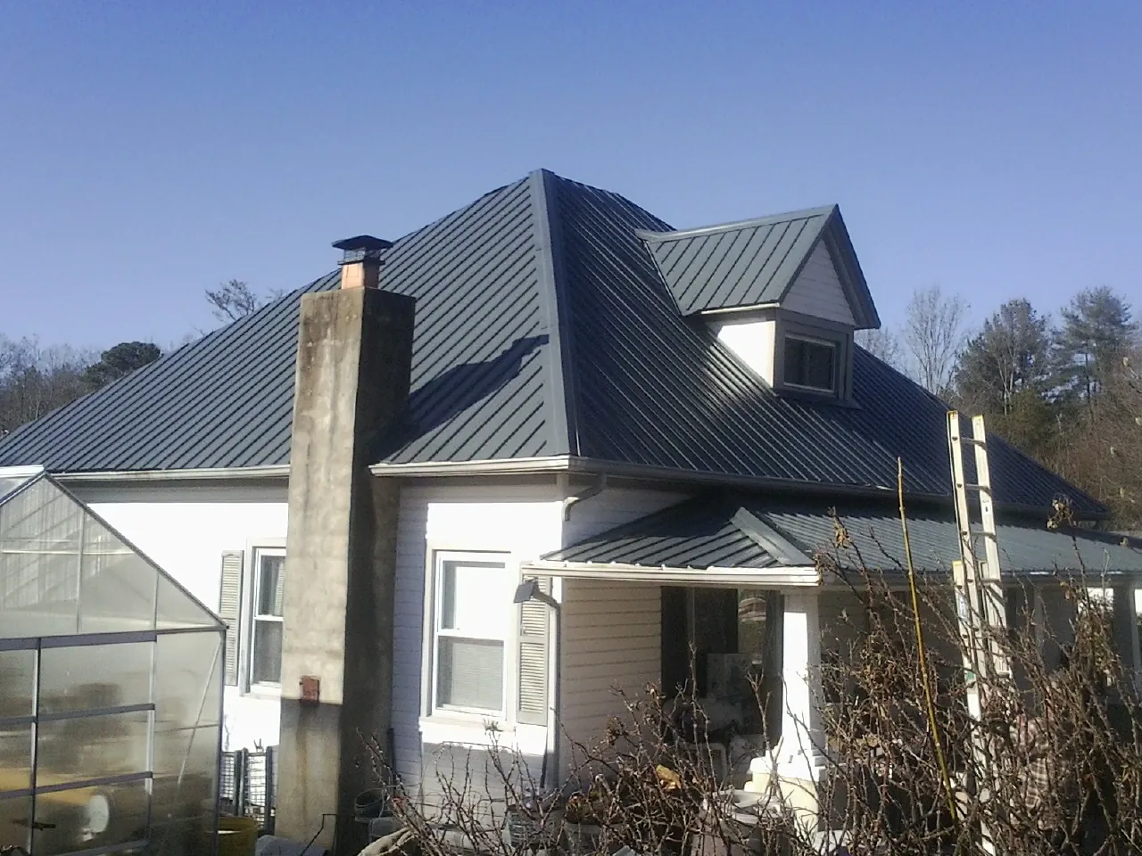 Dark blue standing seam metal roof on a white farmhouse with dormer — Slate & Tile Roof Repair by Roofing Brothers in Bunker Hill