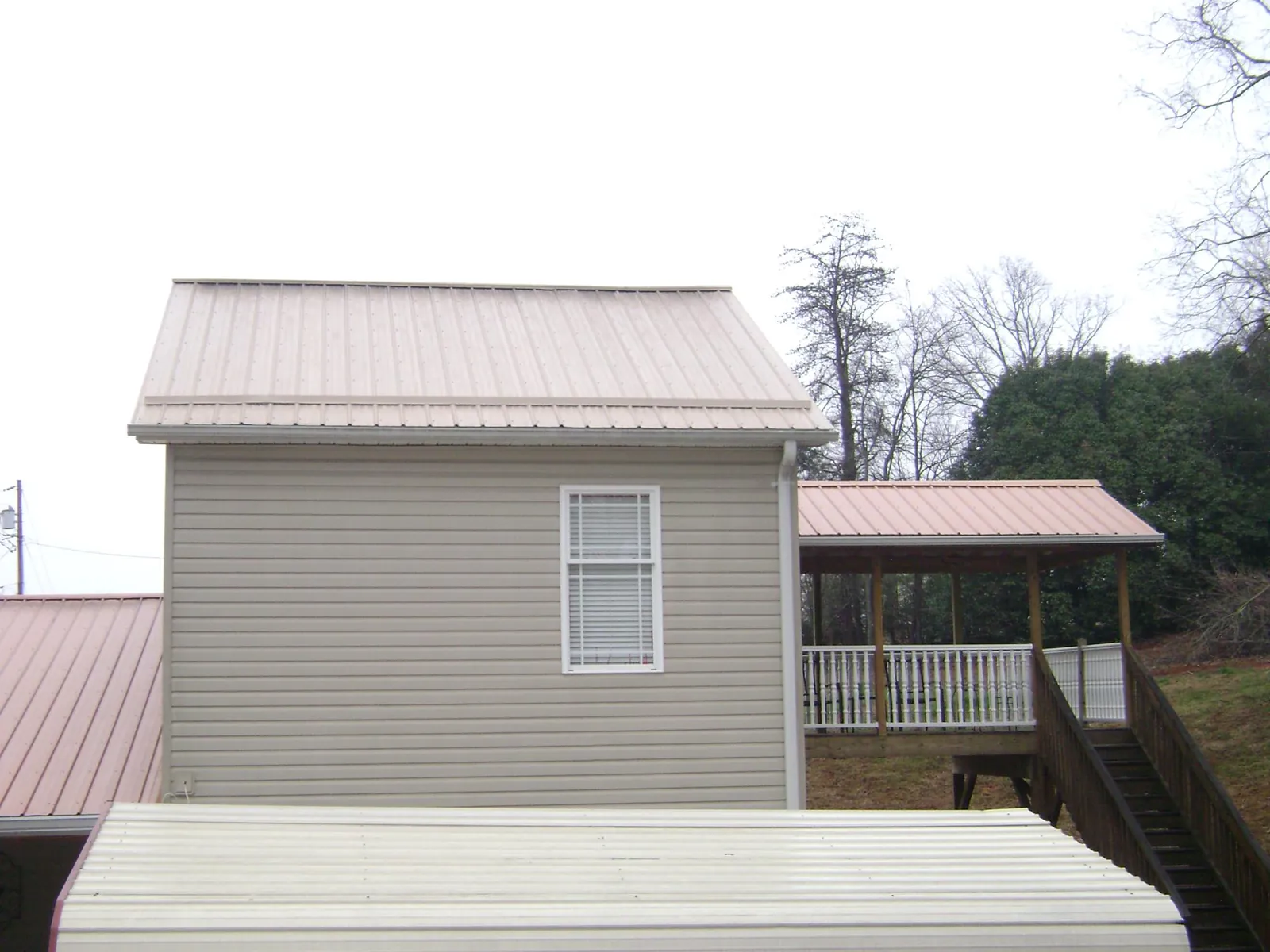 Tan metal roofs on a two story addition and attached porch, from a Roof Replacement job in Bunker Hill