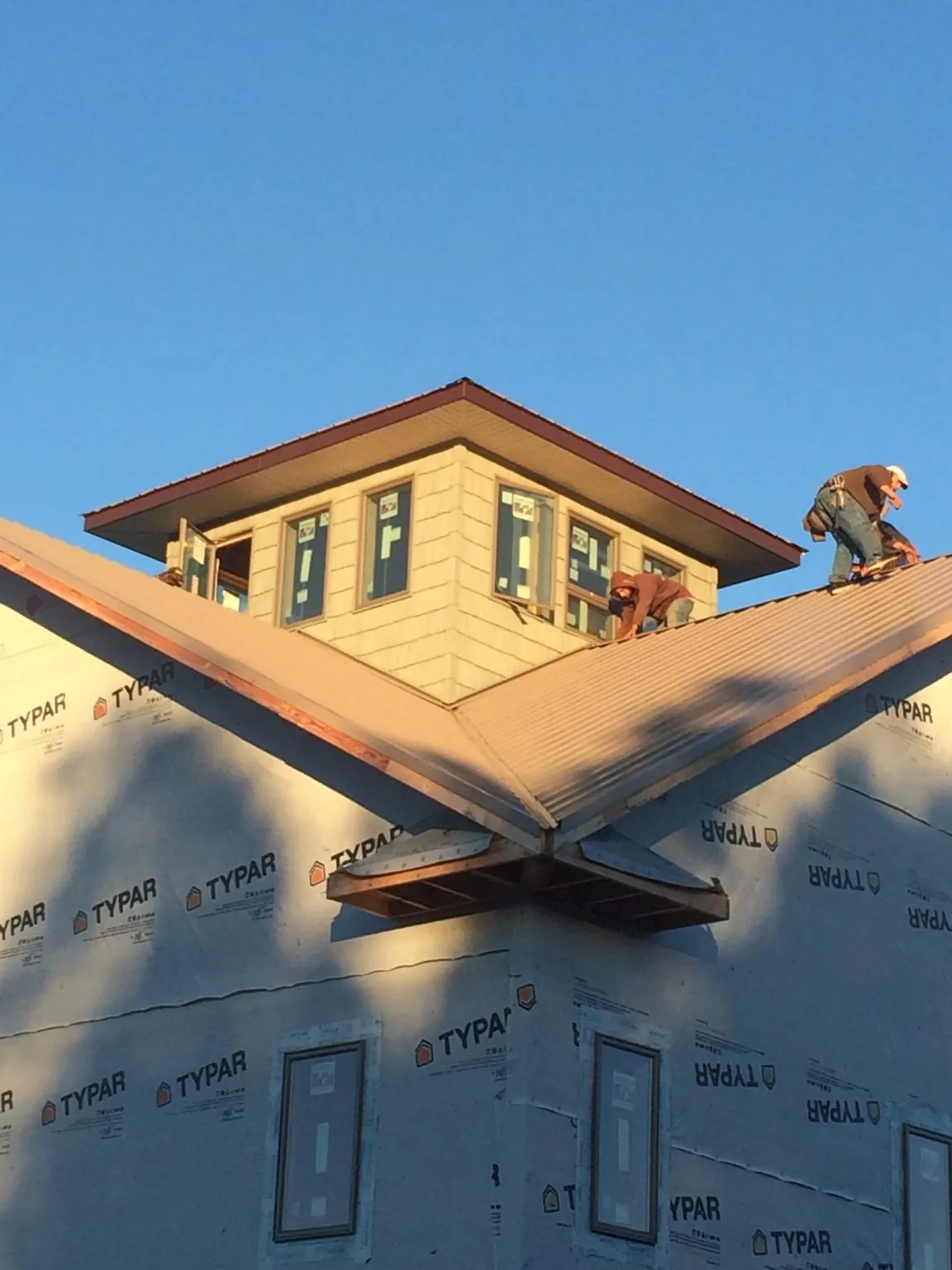 Roofers working around a rooftop cupola on a new metal roof at sunset — Roof Waterproofing in Bunker Hill by Roofing Brothers